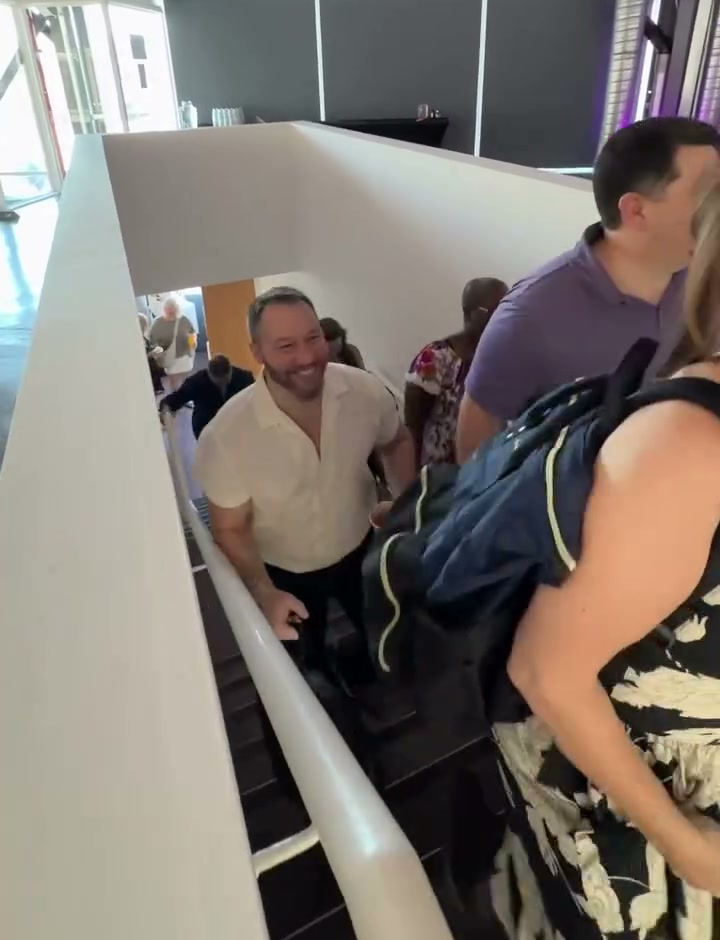A smiling attendee climbing the stairs into the purple-lit Cape Town seminar venue